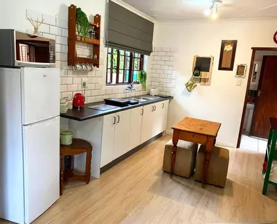 a kitchen with a white refrigerator and a table at Piano Inn in Centurion