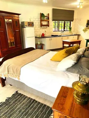 a bedroom with a large white bed and a kitchen at Piano Inn in Centurion