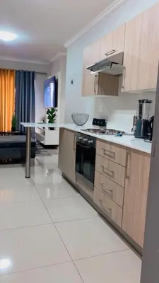a kitchen with wooden cabinets and a white tile floor at Stunning One Bedroom Apartment in Midrand in Midrand