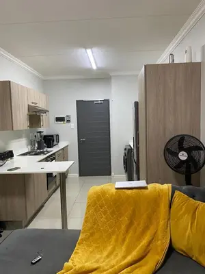 a kitchen with a yellow blanket on a couch in a room at Stunning One Bedroom Apartment in Midrand in Midrand