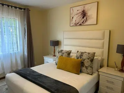 a bedroom with a bed with a yellow pillow on it at 2e - No load shedding 2 bed home to relax into in Centurion