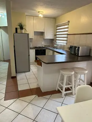 a kitchen with a refrigerator and two bar stools at 2e - No load shedding 2 bed home to relax into in Centurion