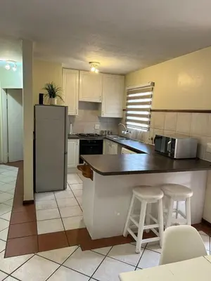 a kitchen with a refrigerator and two bar stools at 2e - No load shedding 2 bed home to relax into in Centurion