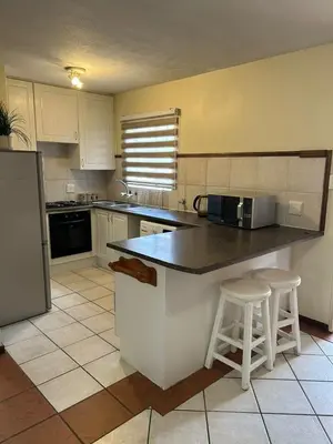 a kitchen with a counter and two stools in it at 2e - No load shedding 2 bed home to relax into in Centurion