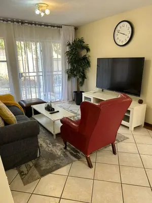 a living room with a red chair and a flat screen tv at 2e - No load shedding 2 bed home to relax into in Centurion