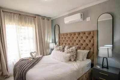 a bedroom with a white bed with a large window at Serenity at Homely Escapes in Phalaborwa
