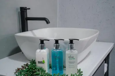 a white sink and three bottles of soap on a counter at Serenity at Homely Escapes in Phalaborwa