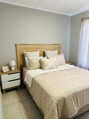 a bedroom with a large bed and a night stand at Homely Stay 2 in Kempton Park