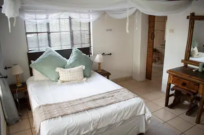 a bedroom with a bed with blue pillows and a window at Namagong in Marloth Park