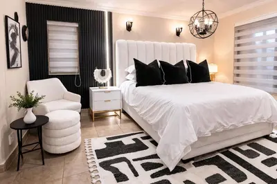 a white bedroom with a white bed and a chair at 156 Euphoria Boutique Villa - Euphoria Golf Estate Hydro in Naboomspruit