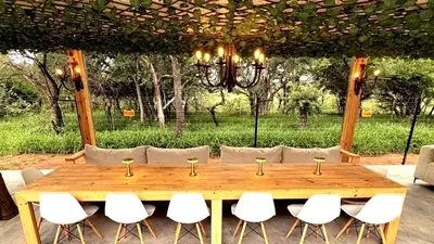 a wooden table with white chairs around it at 156 Euphoria Boutique Villa - Euphoria Golf Estate Hydro in Naboomspruit