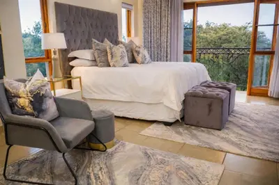 a bedroom with a bed and a chair and a window at 156 Euphoria Boutique Villa - Euphoria Golf Estate Hydro in Naboomspruit