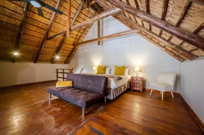 a bedroom with a bed and a couch and a chair at Raptors Wildlife Escapes in Hoedspruit