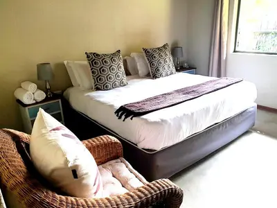 a bedroom with a bed and a chair in a room at Raptors Wildlife Escapes in Hoedspruit