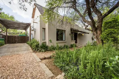a white house with a tree and a yard at Raptors Wildlife Escapes in Hoedspruit