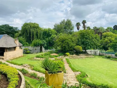 a garden with a lawn and a fence and trees at The Adress in Midrand