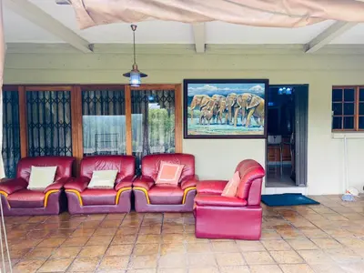 a room with two red chairs and a painting of elephants at The Adress in Midrand