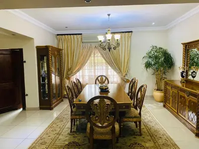 a dining room with a wooden table and chairs at The Adress in Midrand