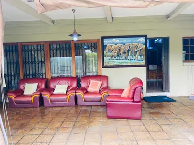 a living room with red leather chairs and a painting of elephants at The Adress in Midrand