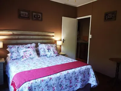 a bedroom with a bed with a pink blanket and pillows at Dublin Guest House in Sabie