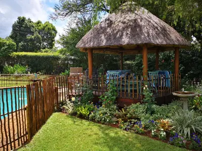 a garden with a gazebo with chairs and flowers at Dublin Guest House in Sabie