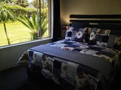 a bed with a quilt on it next to a window at Dublin Guest House in Sabie
