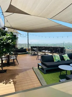 a rooftop patio with a couch and tables and chairs at French love, Menlyn Maine in Pretoria