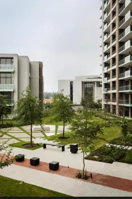 a park with benches and trees in front of a building at French love, Menlyn Maine in Pretoria