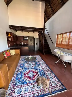 a living room with a couch and a dog on a rug at The loft farmhouse in Roodeplaat area in Wallmannstal