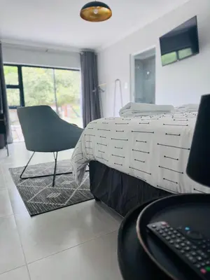 a bedroom with a bed and a chair and a desk at Nelspruit Modern Apartment #2 - Self Check-In in Nelspruit