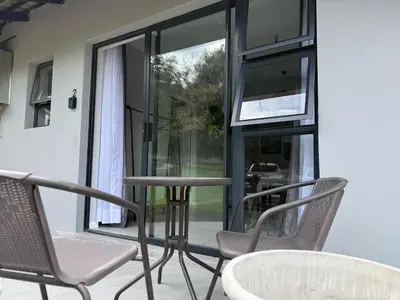 a porch with chairs and a table and a window at Nelspruit Modern Apartment #2 - Self Check-In in Nelspruit
