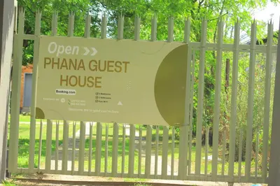an open plan guest house sign on a fence at Phana Quest house in Evander