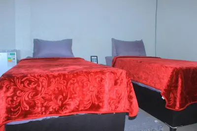 a bedroom with two beds with red comforter at Phana Quest house in Evander
