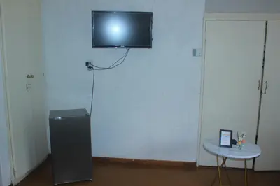 a television on the wall of a room with a table at Phana Quest house in Evander