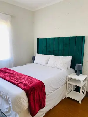a bedroom with a large bed with a green headboard at Phana Quest house in Evander