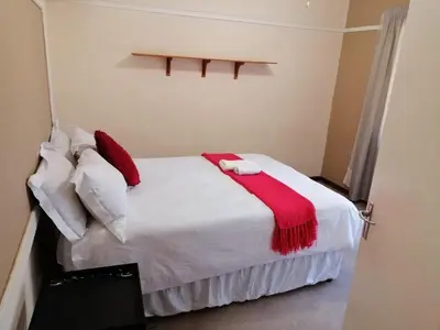 a bedroom with a white bed with a red blanket on it at 4 Seasons Country Club in Vosburg
