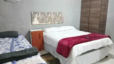 a bedroom with two beds and a chair in it at Elim Pink House Accommodation in Elim