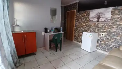 a kitchen with a small table and a refrigerator at Elim Pink House Accommodation in Elim