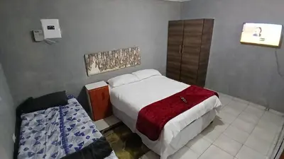 a small bedroom with a bed and a chair at Elim Pink House Accommodation in Elim