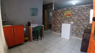 a kitchen with a table and a stone wall at Elim Pink House Accommodation in Elim
