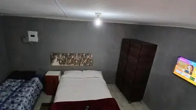 a small bedroom with a bed and a tv at Elim Pink House Accommodation in Elim
