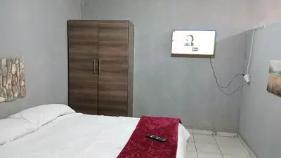 a bedroom with a bed and a tv on the wall at Elim Pink House Accommodation in Elim