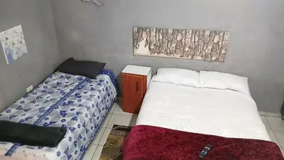 a small bedroom with two beds and a picture on the wall at Elim Pink House Accommodation in Elim