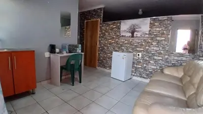 a living room with a couch and a stone wall at Elim Pink House Accommodation in Elim