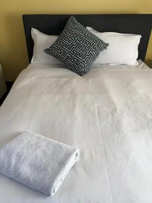 a white bed with two pillows and a white blanket at Nyumbani in Kempton Park