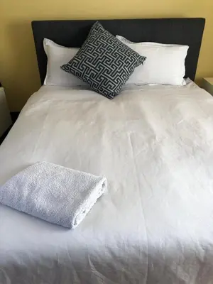 a white bed with two pillows and a towel on it at Nyumbani in Kempton Park