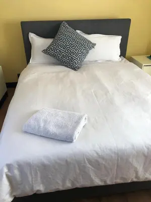 a bed with white sheets and pillows on it at Nyumbani in Kempton Park