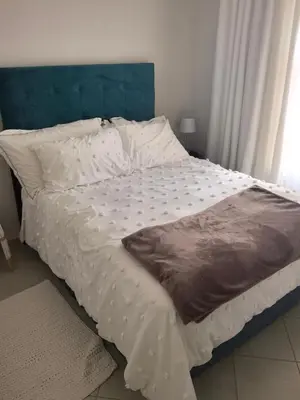 a bed with white sheets and a blue headboard at Lerato's Guesthouse 840 in Polokwane