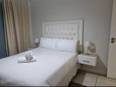 a bedroom with a large white bed and a night stand at Apartment at The Blyde in Pretoria