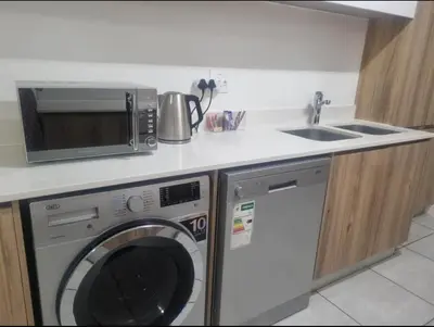 a kitchen with a washing machine and a sink at Apartment at The Blyde in Pretoria